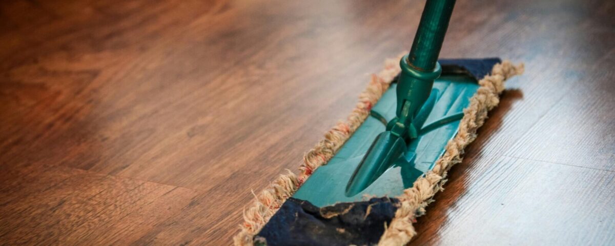 A detailed view of a mop cleaning a wooden floor, showing texture and pattern.