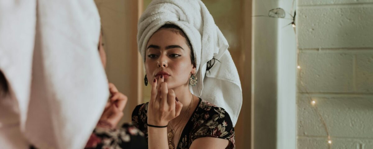 woman putting makeup in front of mirror